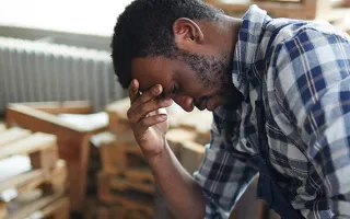 A man in pain, holding his stomach and head.